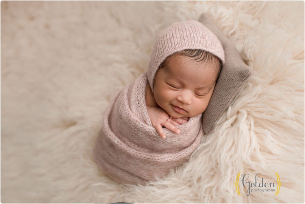 baby girl smiling white wrapped on a white rug
