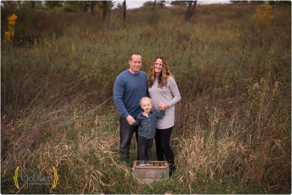 family of three posing in the grass outside Chicago IL