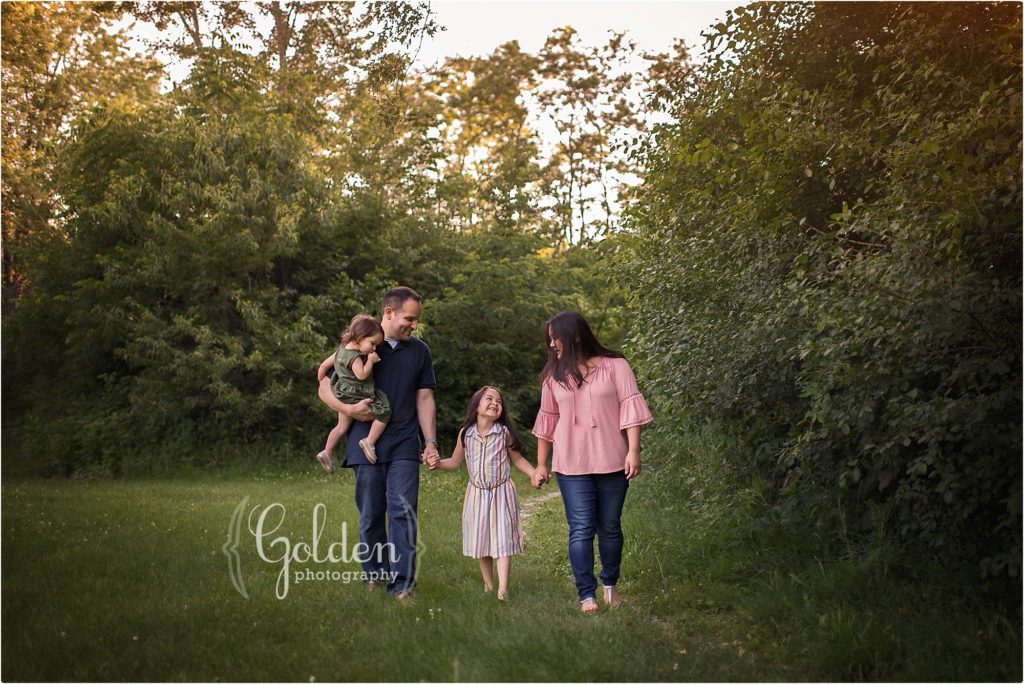 family of four holding hands and walking outside