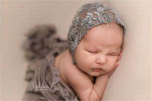 baby girl wearing grey bonnet in newborn photography studio in northwest Chicago suburbs