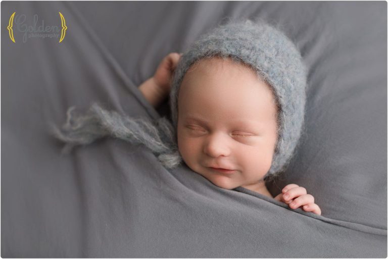 baby boy wearing bonnet and smiling in Chicago suburbs photography studio