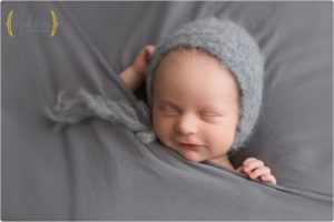 baby boy wearing bonnet and smiling in Chicago suburbs photography studio