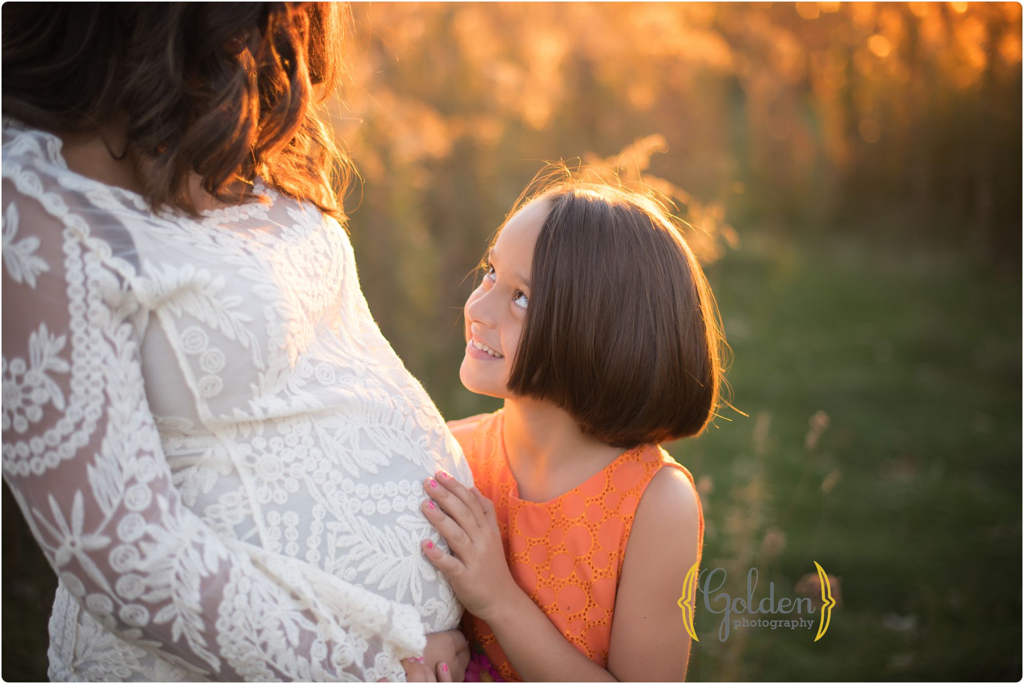 big sister holding mom's belly outside near Chicago IL
