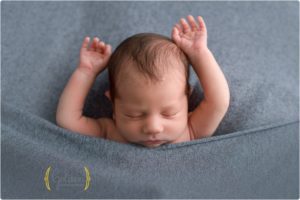 baby boy sleeping with arms up with best Lake County IL newborn photographer