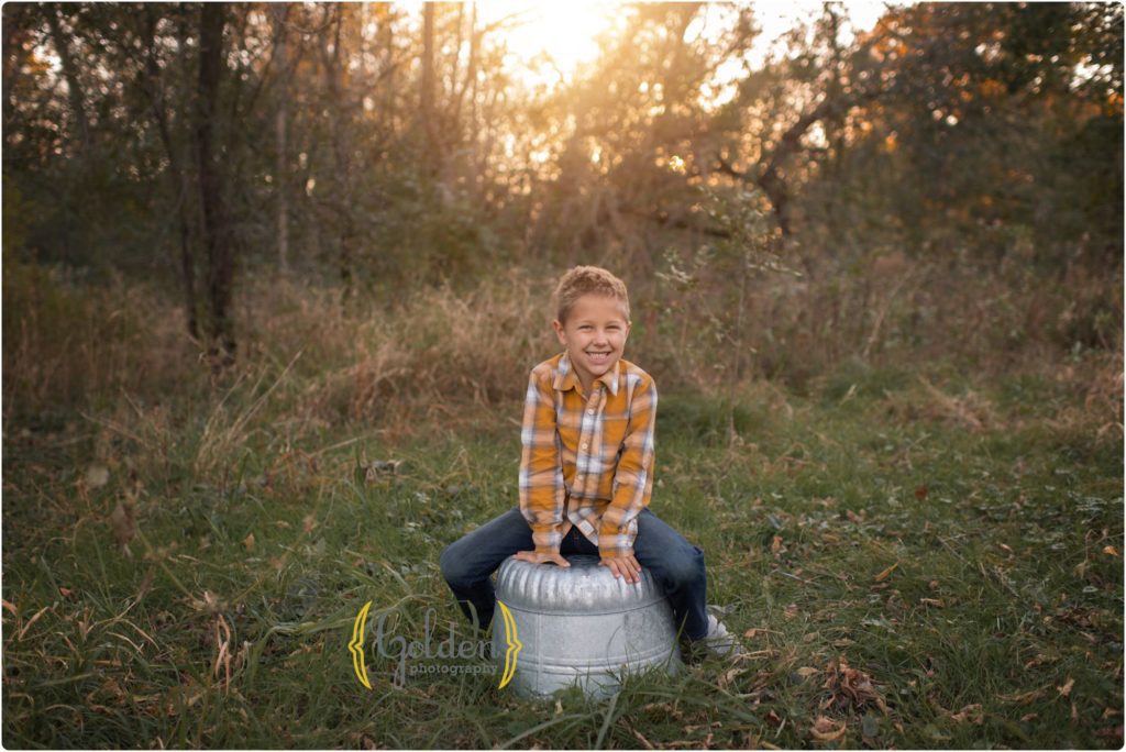 young boy sits on metal tub outside for family photos in Lake County IL