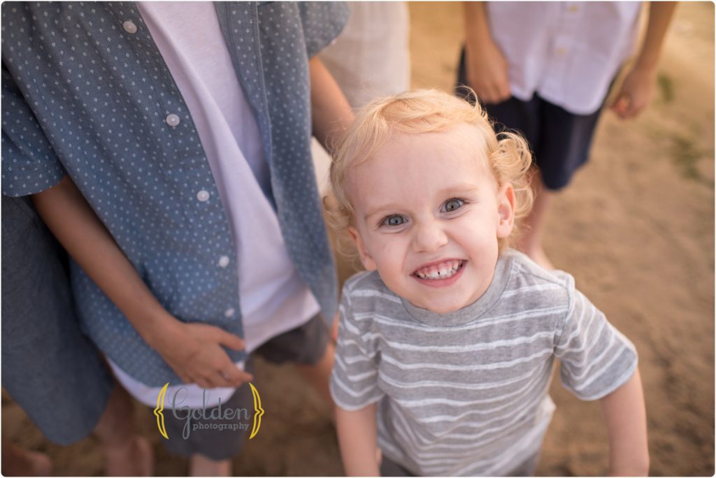 little boy looking up at photographer during family beach photos in lake Zurich IL