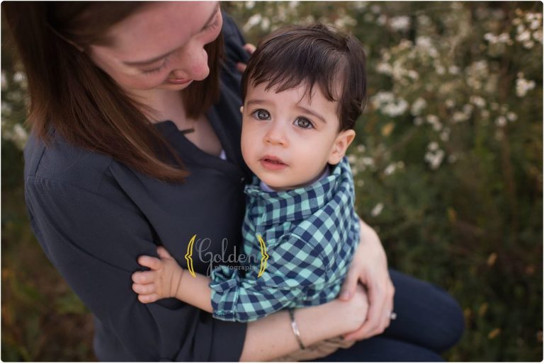 1 year old boy sitting on mom's lap during outdoor family photos near Barrington IL