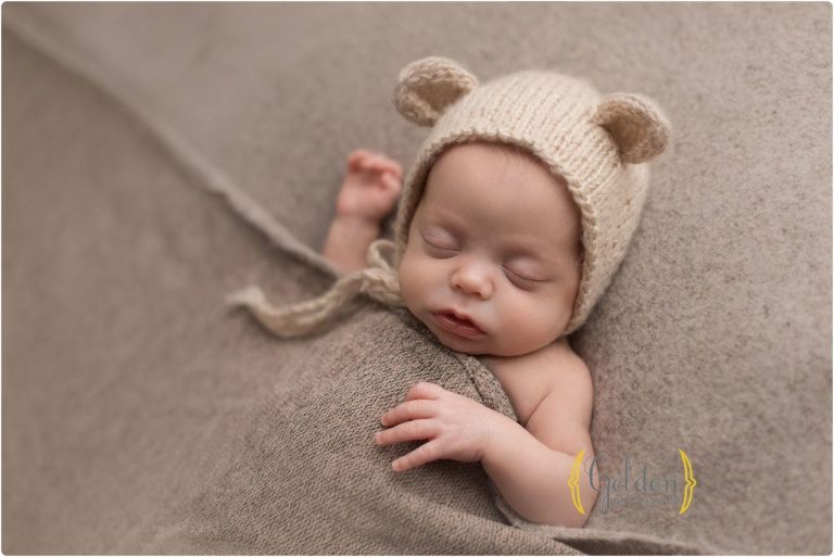 newborn sleeping with bear hat on in newborn photo studio near Barrington Illinois