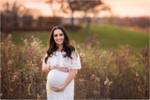 mom holding pregnancy belly in white dress for photos with best maernity photographer near Wilmette IL
