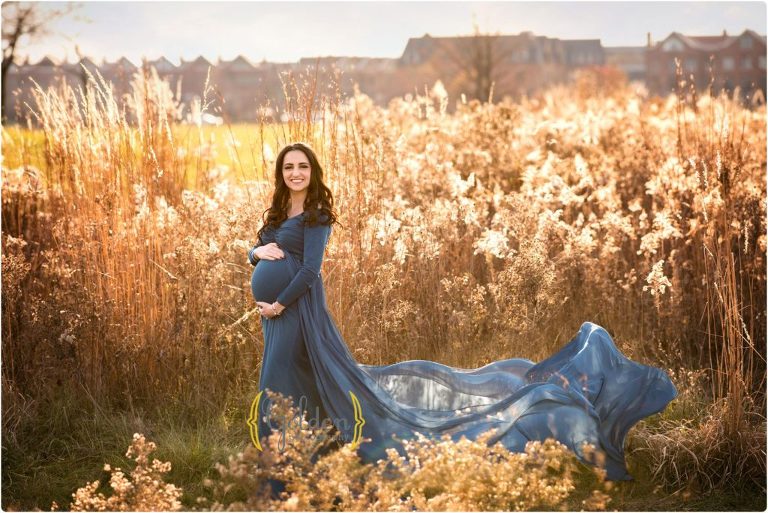 pregnant mom holding belly with dress blowing in the wind for maternity photos in Northbrook IL