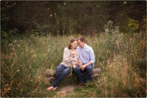 family of three sitting on log for family photographs in lake County Illinois