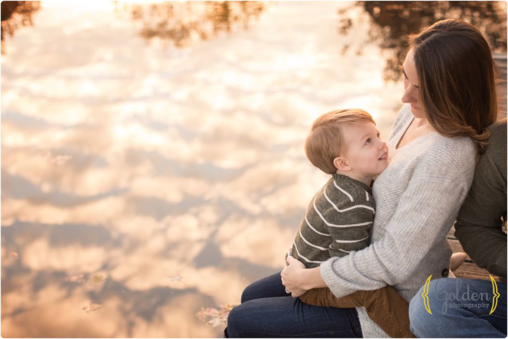 toddler coddling with mom during outdoor family photos on docks with cloud reflection in Barrington IL