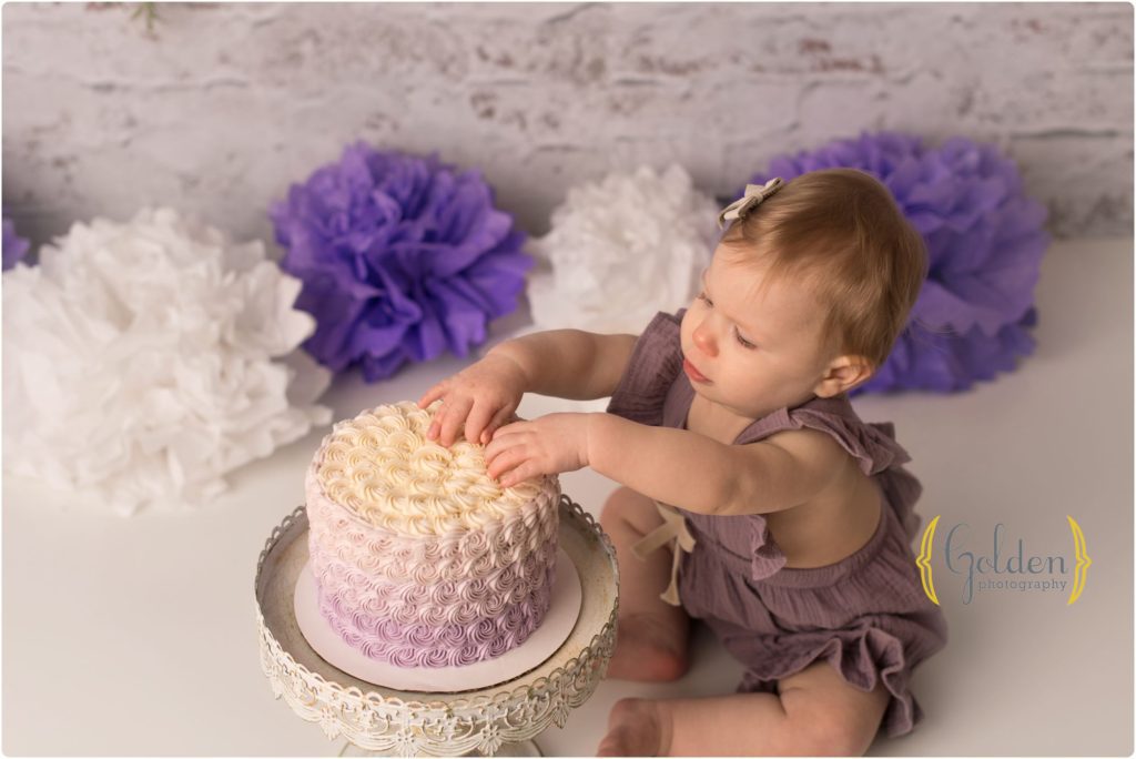 1 year old girl smashing cake in photo studio in Barrington IL