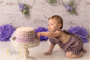 baby girl touching cake for birthday photos