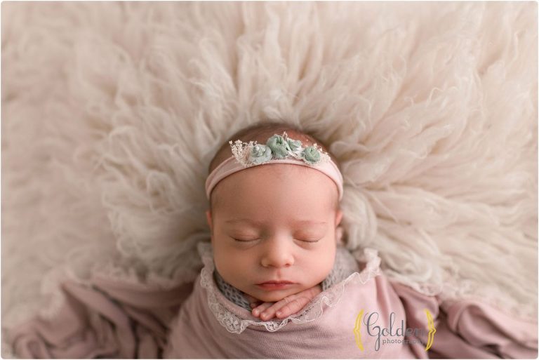 baby girl sleeping on fuzzy rug in photo studio