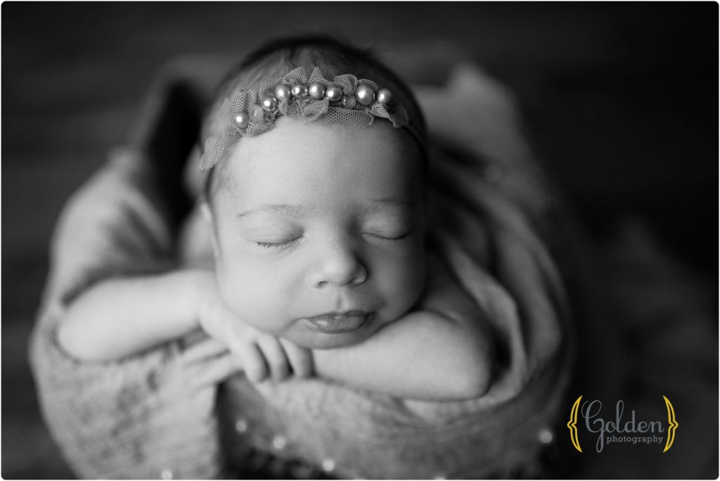 black and white photo of baby girl in crate