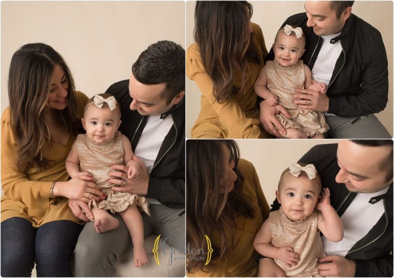 mom and dad cuddling 1 year old daughter in photo studio