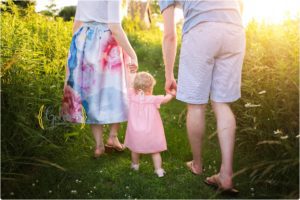 little girl holding parents hand walking away