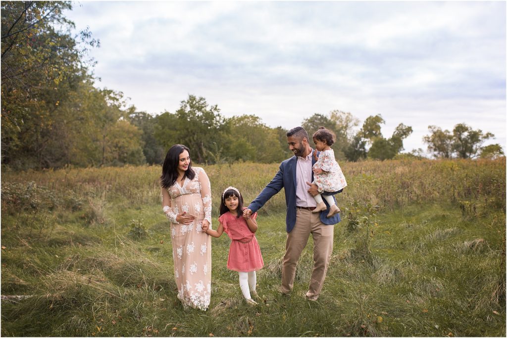 family of four and pregnant mom walking in Lake Zurich IL field