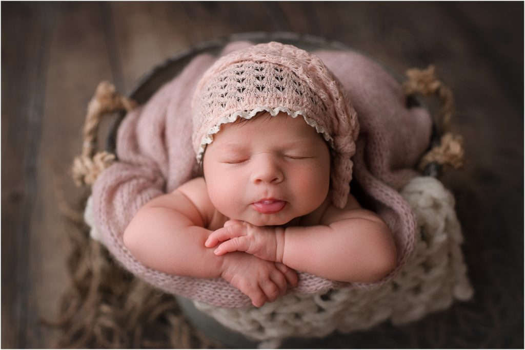 newborn girl posing in bucket for photo session