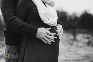 husband and wifes hands on pregnant belly