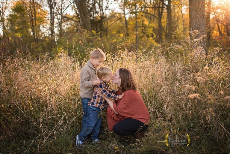 child kissing mom for family photos in a field near Chicago IL