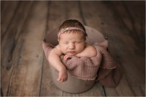 baby asleep in buck on wood floor of newborn studio in Lake County IL