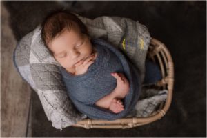 newborn swaddled in blue in a basket for newborn photos near Arlington Heights