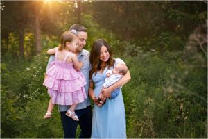 family of four posed with new baby outdoors at Vehe Barn