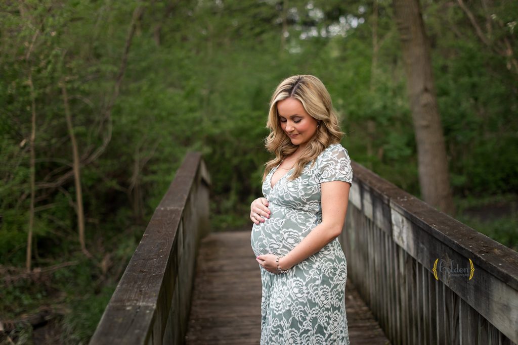 mom holding pregnant belly on a bridge neer Arlington Heights IL