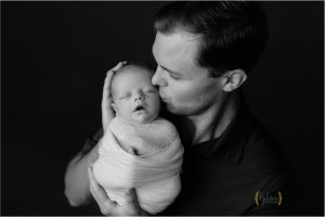 dad kissing baby boy during newbotn photography session