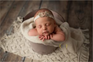 newborn baby girl posed in a bucket for photo session