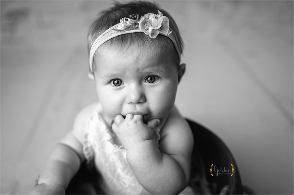 black and white image of baby sucking on fingers during photo session