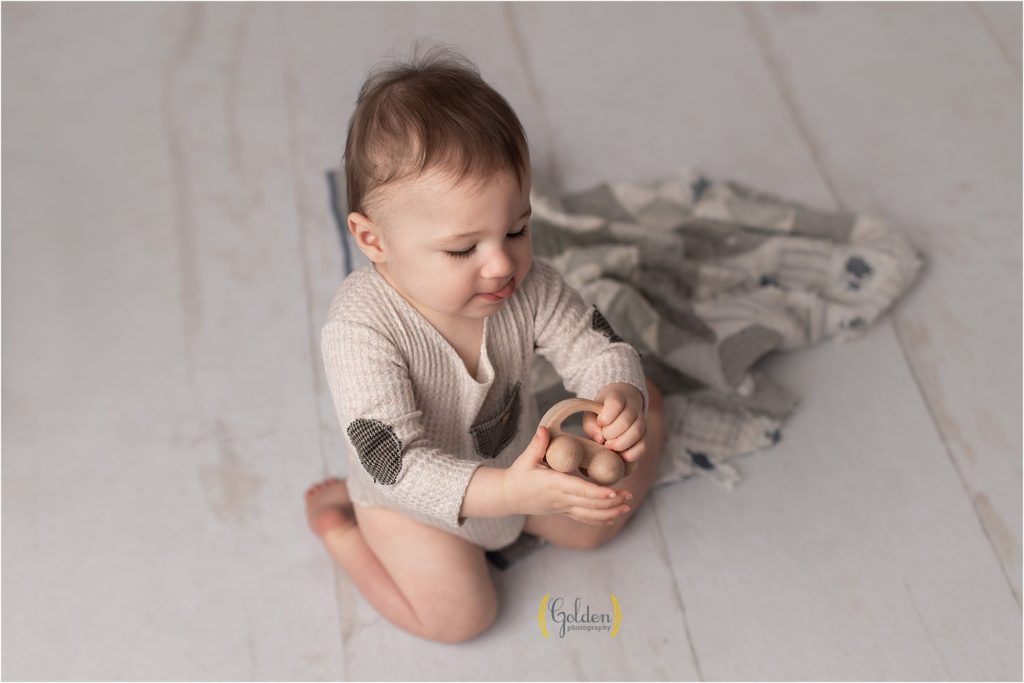 boy plays with wooden toy car in Grayslake photo studio
