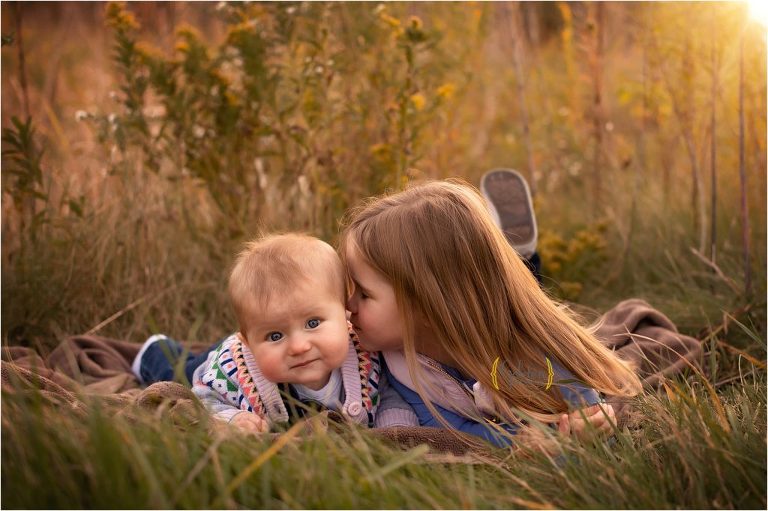 sister kissing baby for outdoor family photos
