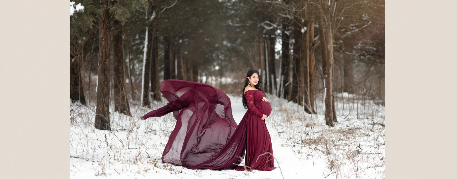 pregnant woman wearing red in tree lines forest in the snow