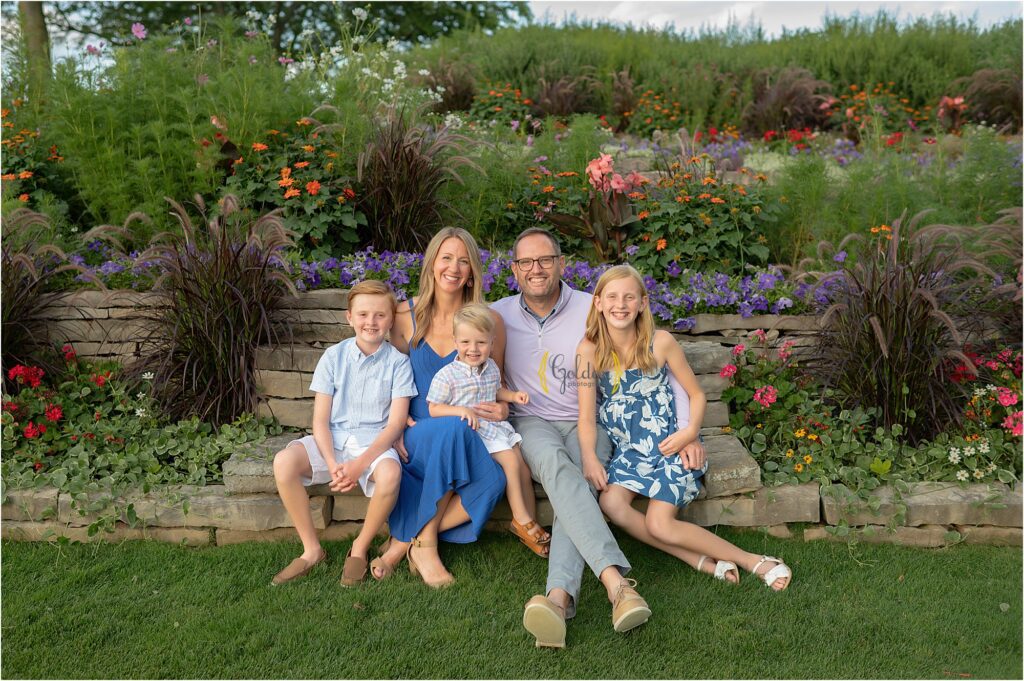 family of 5 seated on a stone bench on the grass at Biltmore Country Club in Barrington Ilinois